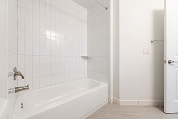 A white bathroom with a white tub and a white door.