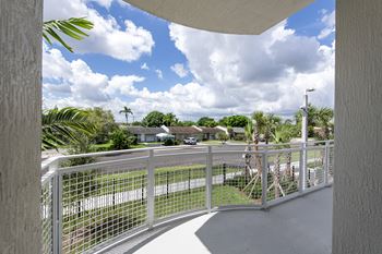 A white fence with a metal railing is in the foreground of a sunny day.