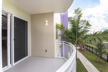 A balcony with a white railing and a palm tree in the background.