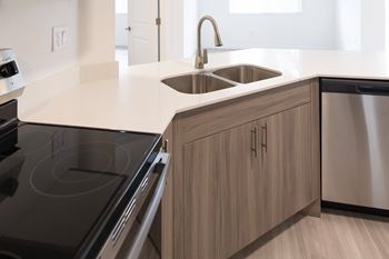 A modern kitchen with a stove, sink, and cabinets.