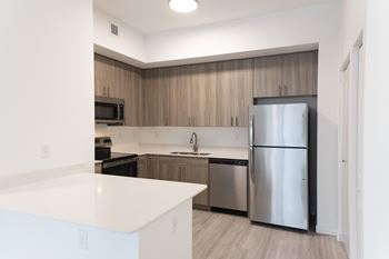 A kitchen with a white counter top and a stainless steel refrigerator.