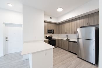 A modern kitchen with a refrigerator, sink, and cabinets.