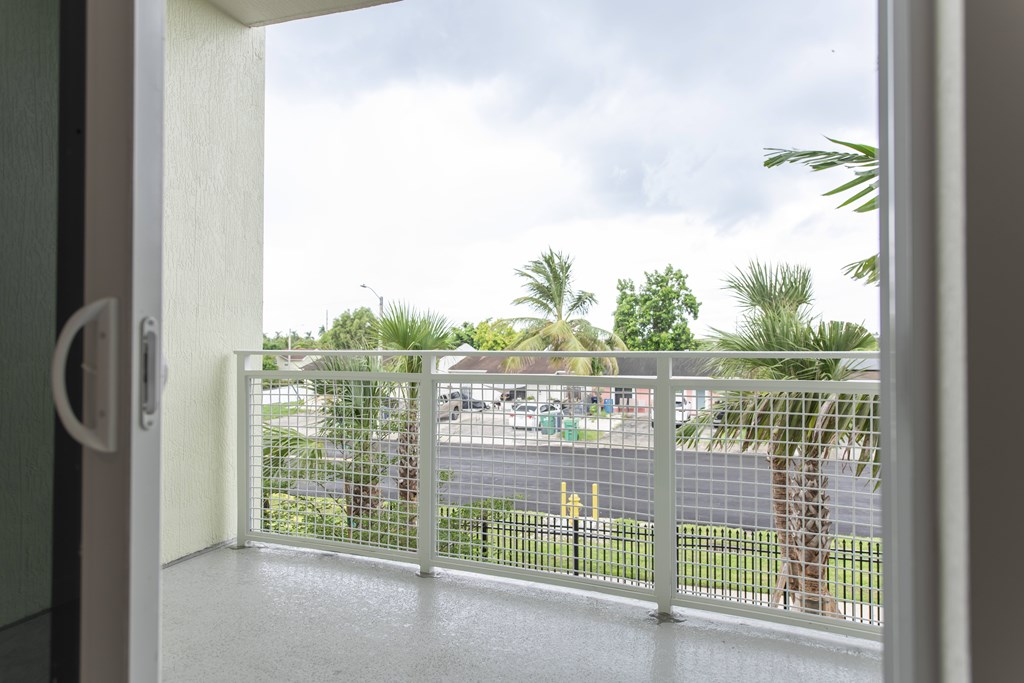 A view from a doorway looking out to a street with a fence and trees.