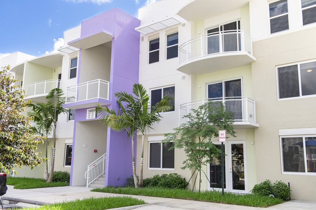 A white and purple building with balconies and windows.