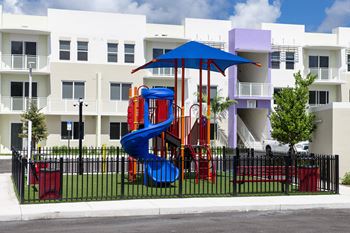 A colorful playground in front of a white apartment building.
