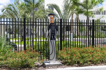 An electric vehicle charging station is located in front of a black fence.