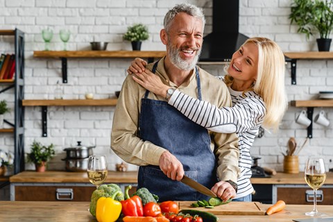 A man and woman are preparing food together in a kitchen.