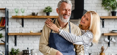 A man and a woman are hugging in a kitchen.