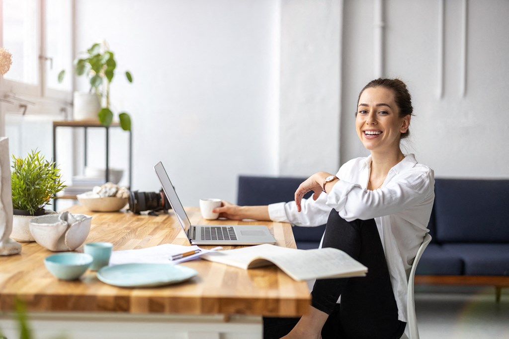A woman is sitting at a table with a laptop and a book.