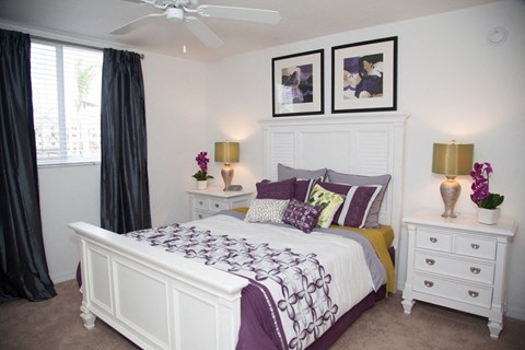 A bedroom with a bed, nightstands, and a ceiling fan.