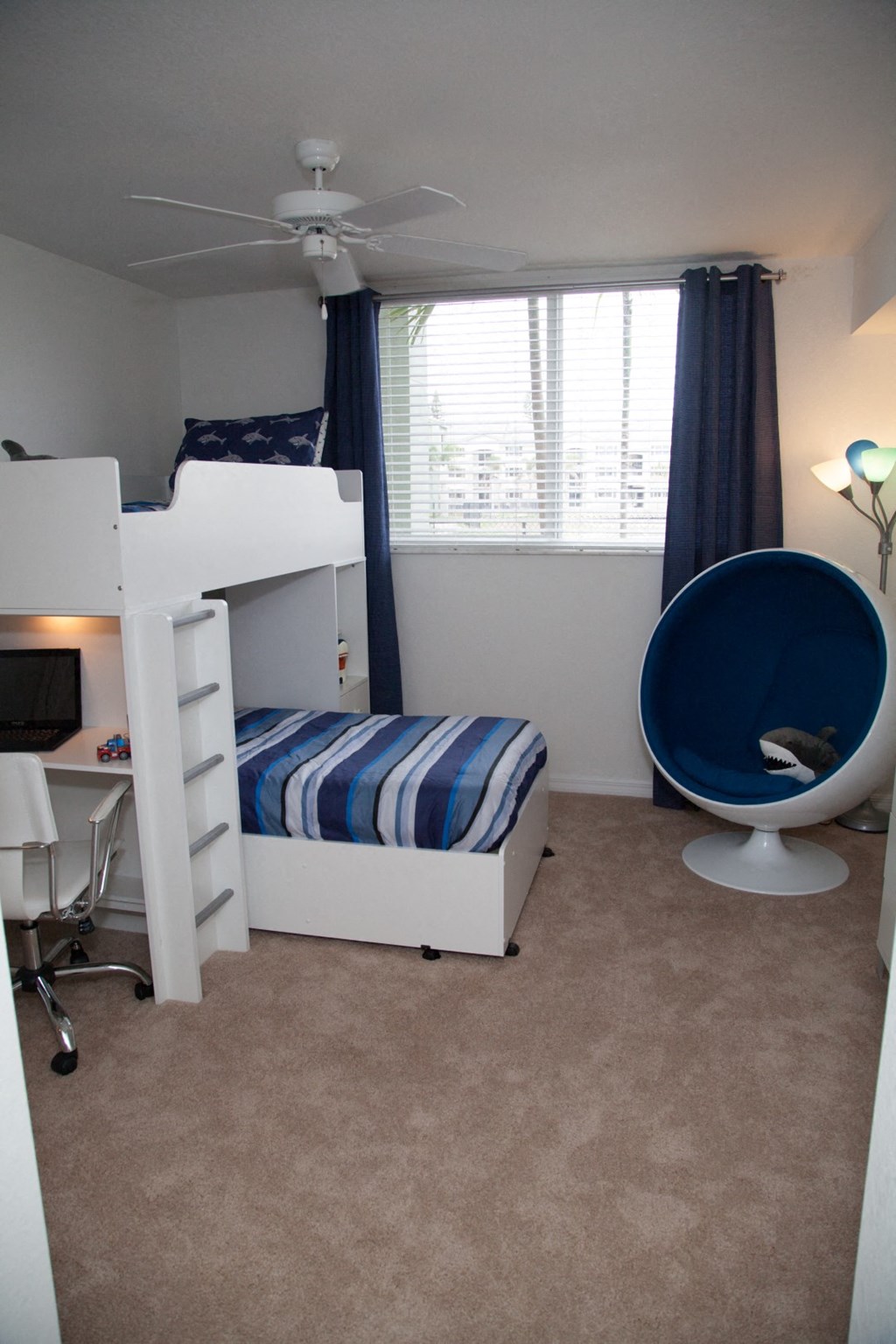 a bedroom with a bunk bed and a chair and a window