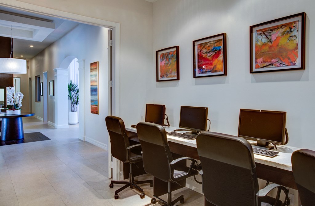 a conference room with a long desk with computers and chairs