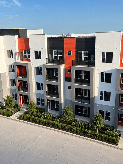 A modern apartment building with balconies and trees in front.