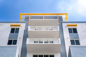a white building with yellow balconies and a blue sky