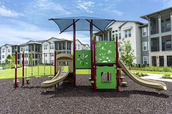 A playground with a green slide and a red and green play structure.