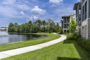 A pathway runs alongside a body of water with a building on the right.