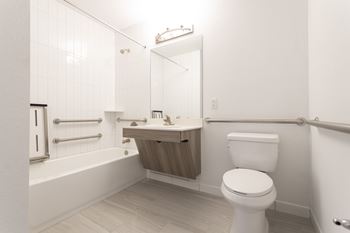 A white toilet is in a bathroom with a white tub and sink.
