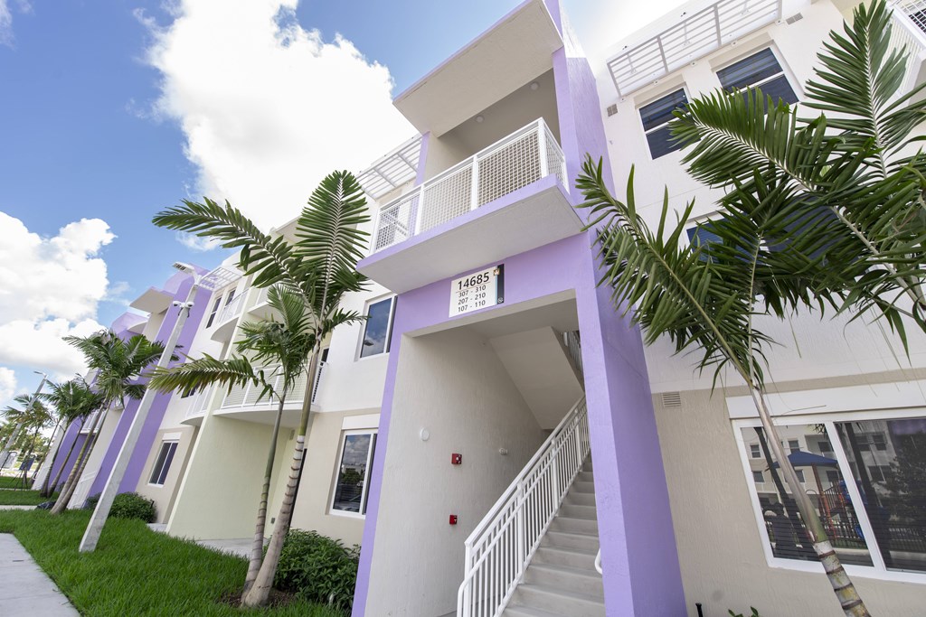 A white and purple building with a staircase leading to the second floor.