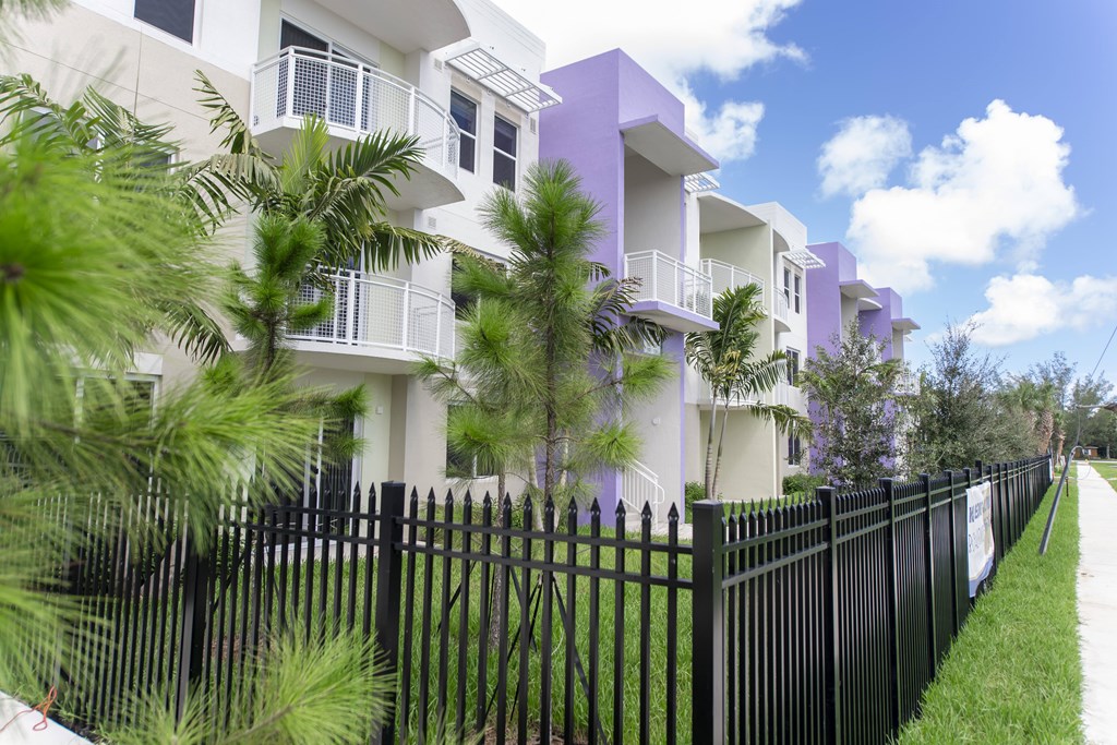 A row of houses with a black fence in front.