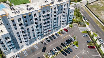 an aerial view of an apartment building and a parking lot full of cars