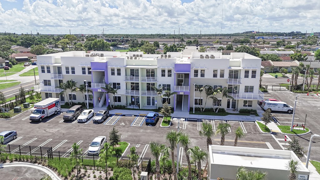 A large white building with a purple accent is surrounded by a parking lot.