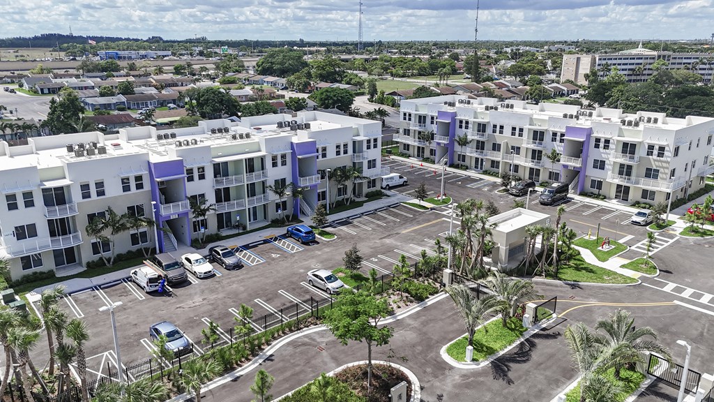 A large apartment complex with a parking lot in front.