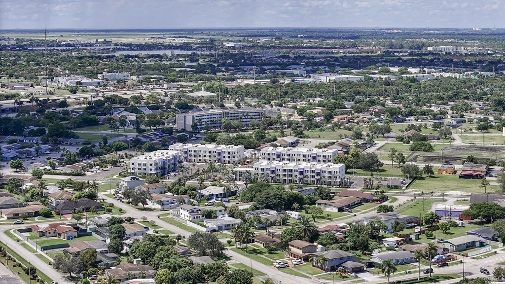 A residential area with apartment buildings and houses surrounded by trees.