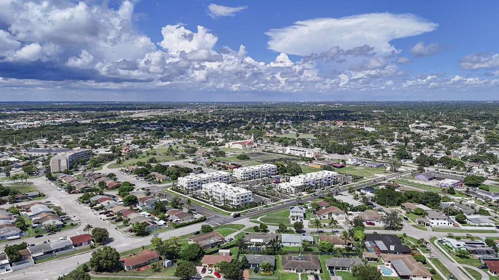 A bird's eye view of a residential area with houses, roads, and a large cloud formation.