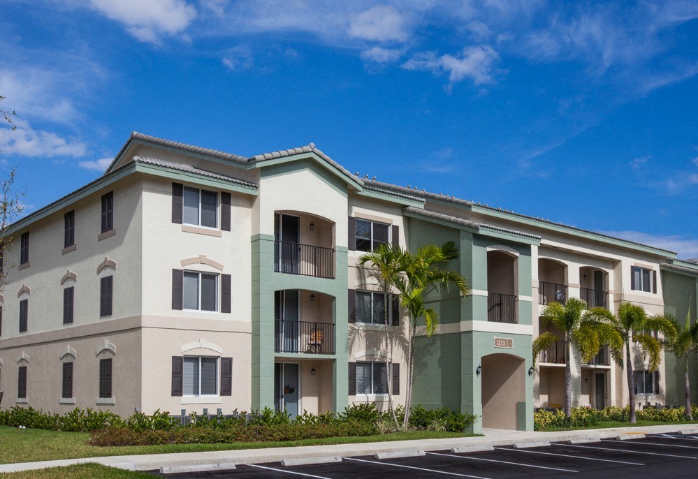 a large apartment building with palm trees in front of it