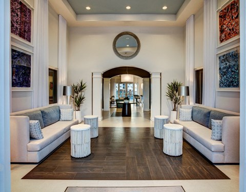 A spacious hallway with white couches and a large mirror on the wall.