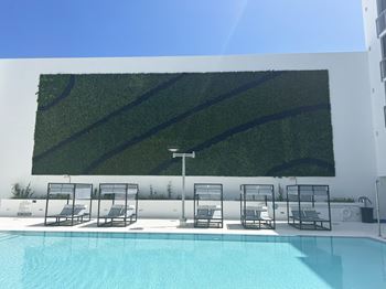 a green wall on the side of a building next to a pool