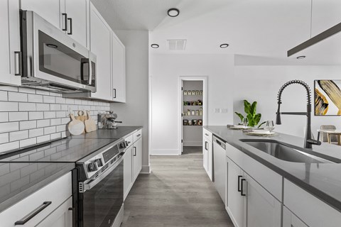 A modern kitchen with white cabinets and a black countertop.