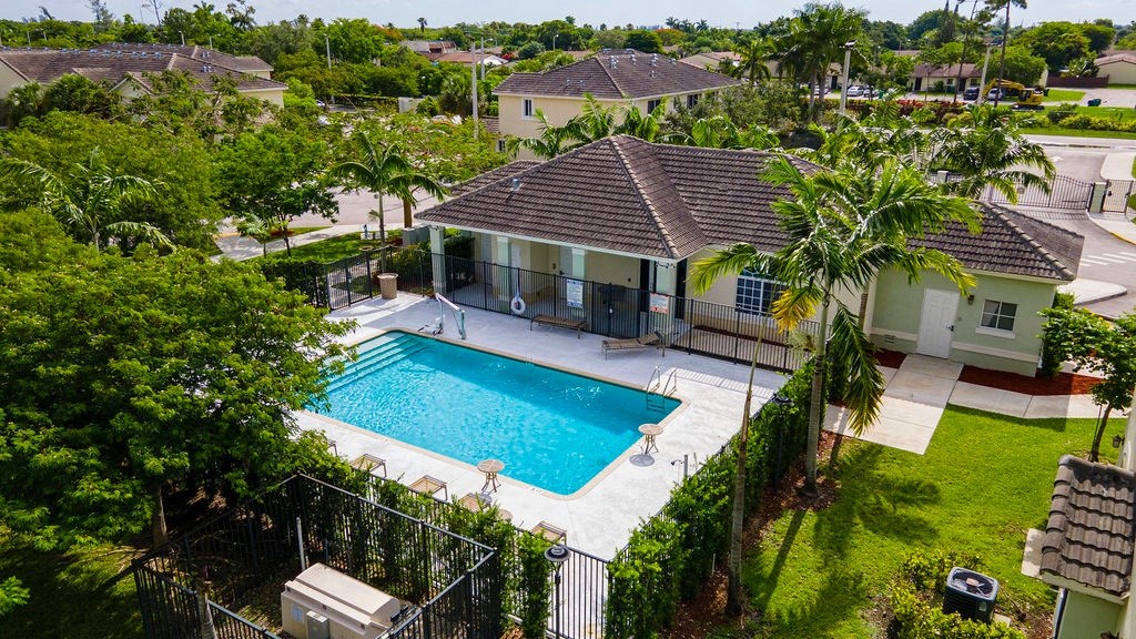 a backyard with a swimming pool and a house with palm trees