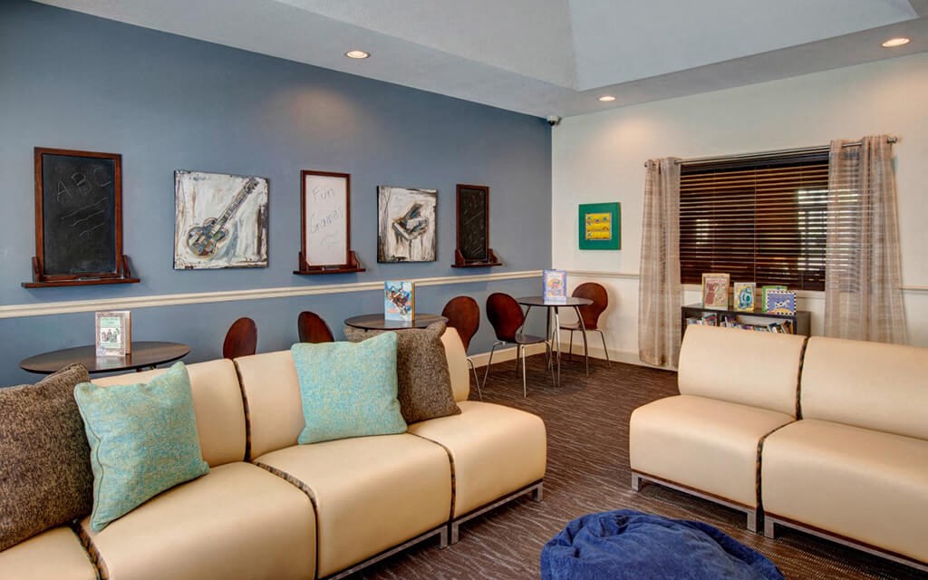 a living room with couches and chairs and paintings on the wall