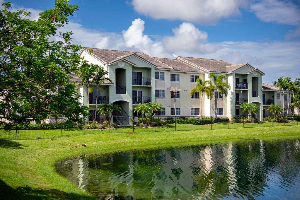 a large pond in front of a building with palm trees