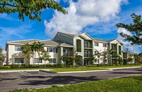 A large, modern apartment building with a parking lot in front.