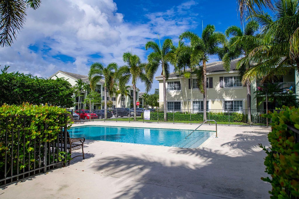 a swimming pool in front of a building with palm trees