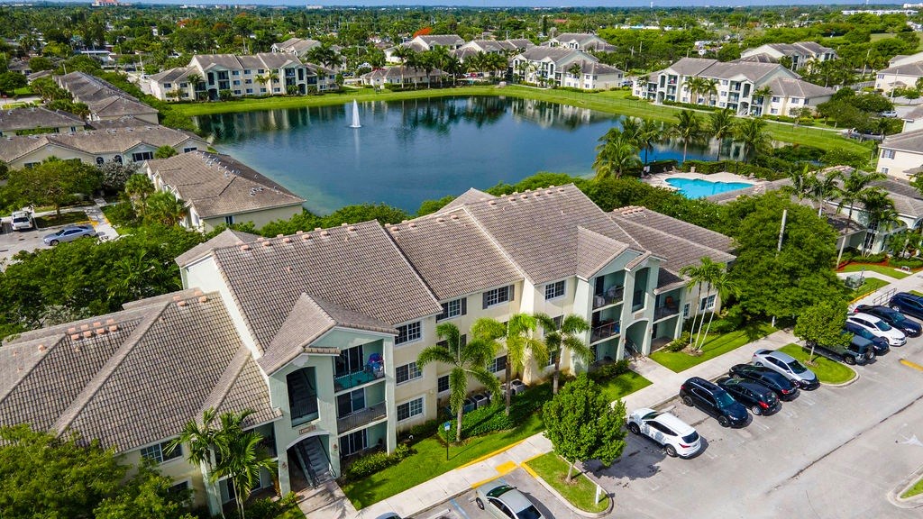 an aerial view of an apartment complex with a lake and parking lot