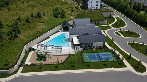 A large building with a pool and tennis court in front.