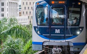 A blue and white train with the letter M on it is on a track.