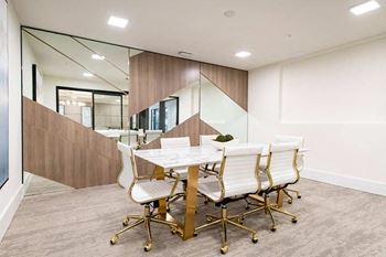 A conference room with a table surrounded by white chairs.