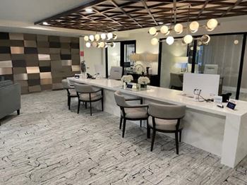 A well-lit salon with a white counter and brown chairs.