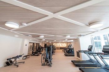 A gym with a variety of exercise equipment including treadmills, weights, and exercise bikes.