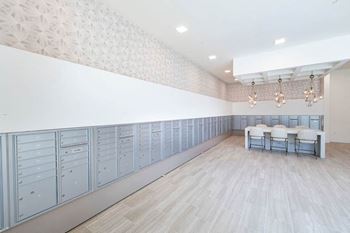 A room with a long row of lockers on the wall and a table with chairs in the middle.
