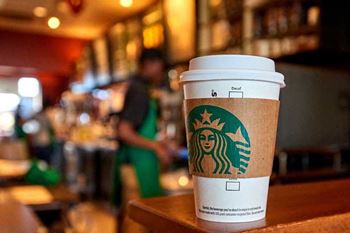 A Starbucks cup sits on a table with a blurred background.