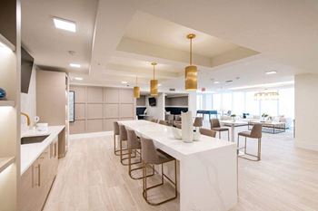 A modern kitchen with a long white island and chairs.