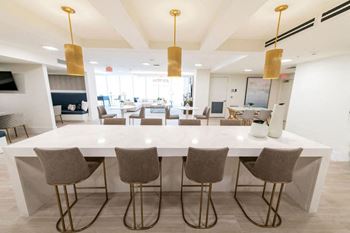 A white dining table with four chairs and three hanging lights.