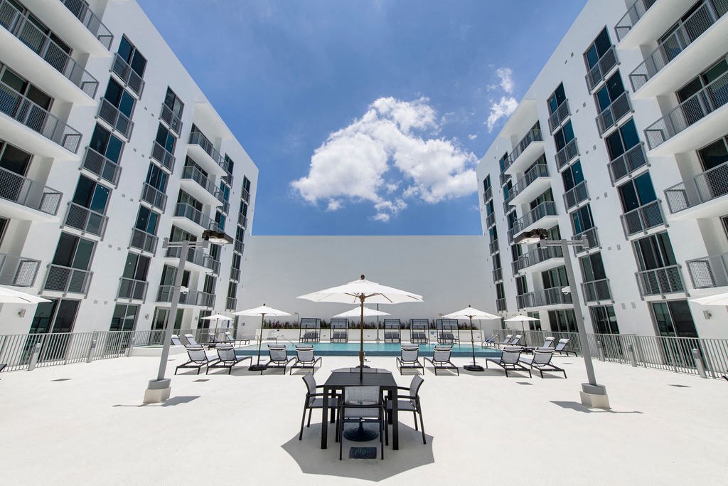 a large patio with a dining table and chairs in between two tall buildings