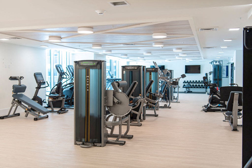 a large fitness room with cardio machines and weights