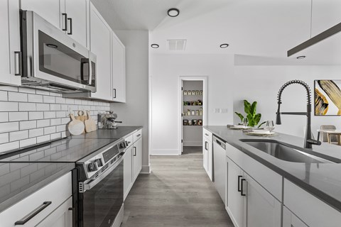 A modern kitchen with white cabinets and black countertops.